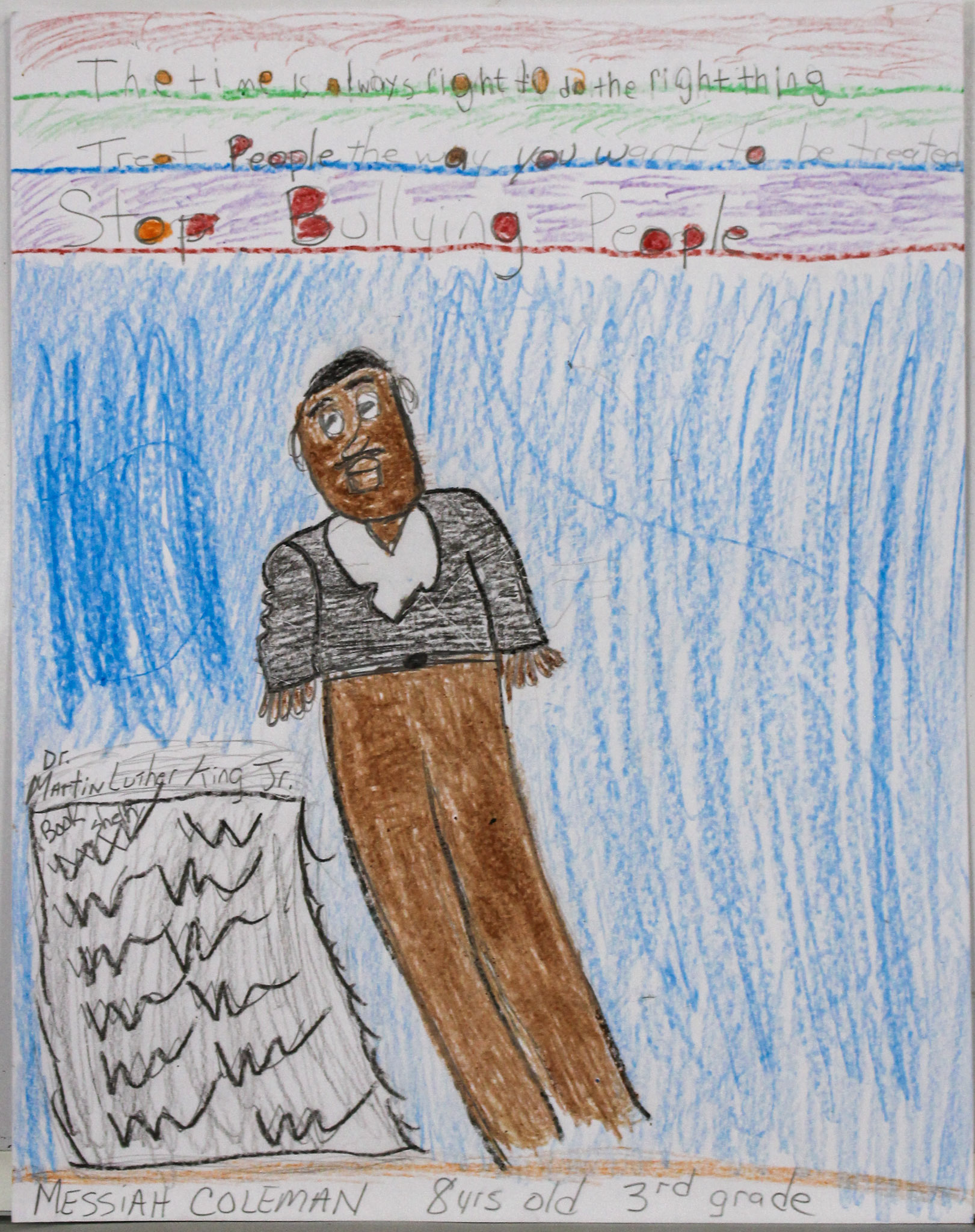 A colored pencil drawing of MLK by a book shelf, including the text "treat people how you want to be treated" and "stop bullying people"