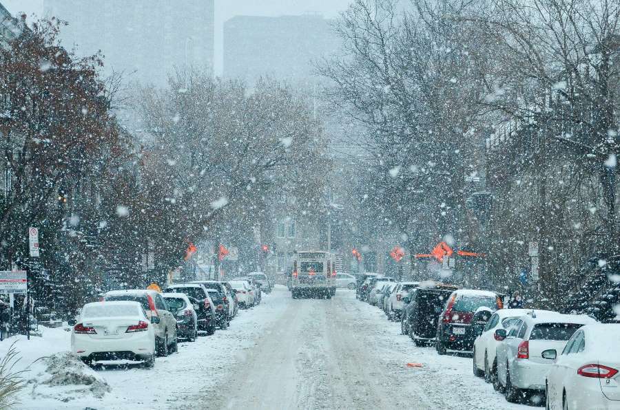 Car lined street in winter with snow falling